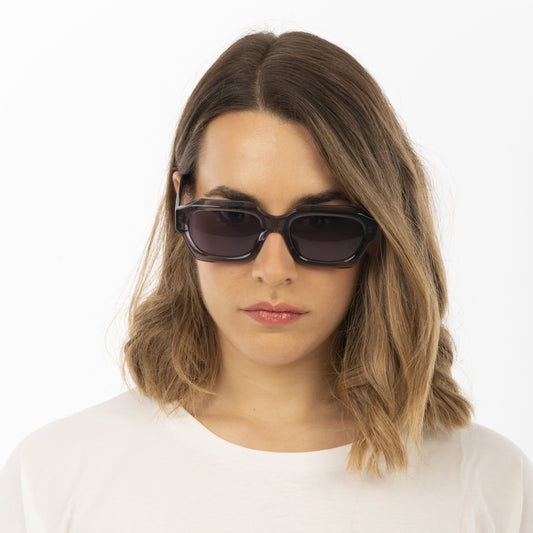 Woman wearing dark sunglasses with a plain white background