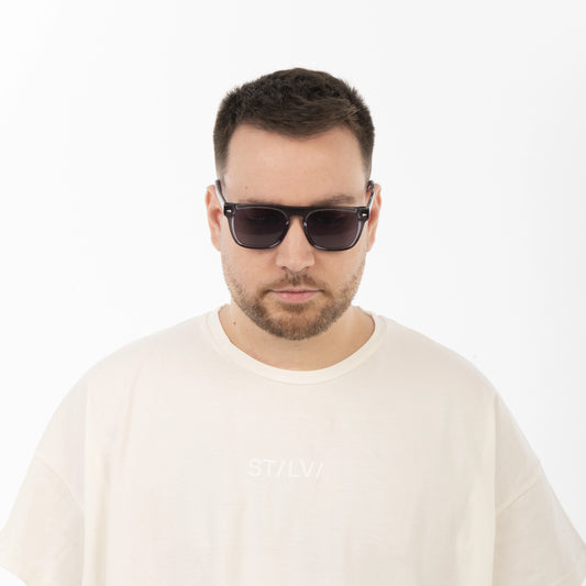 Man wearing sunglasses and a beige sweater on a white background