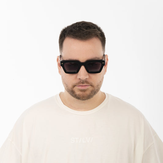 Man wearing black sunglasses and a beige shirt on a white background