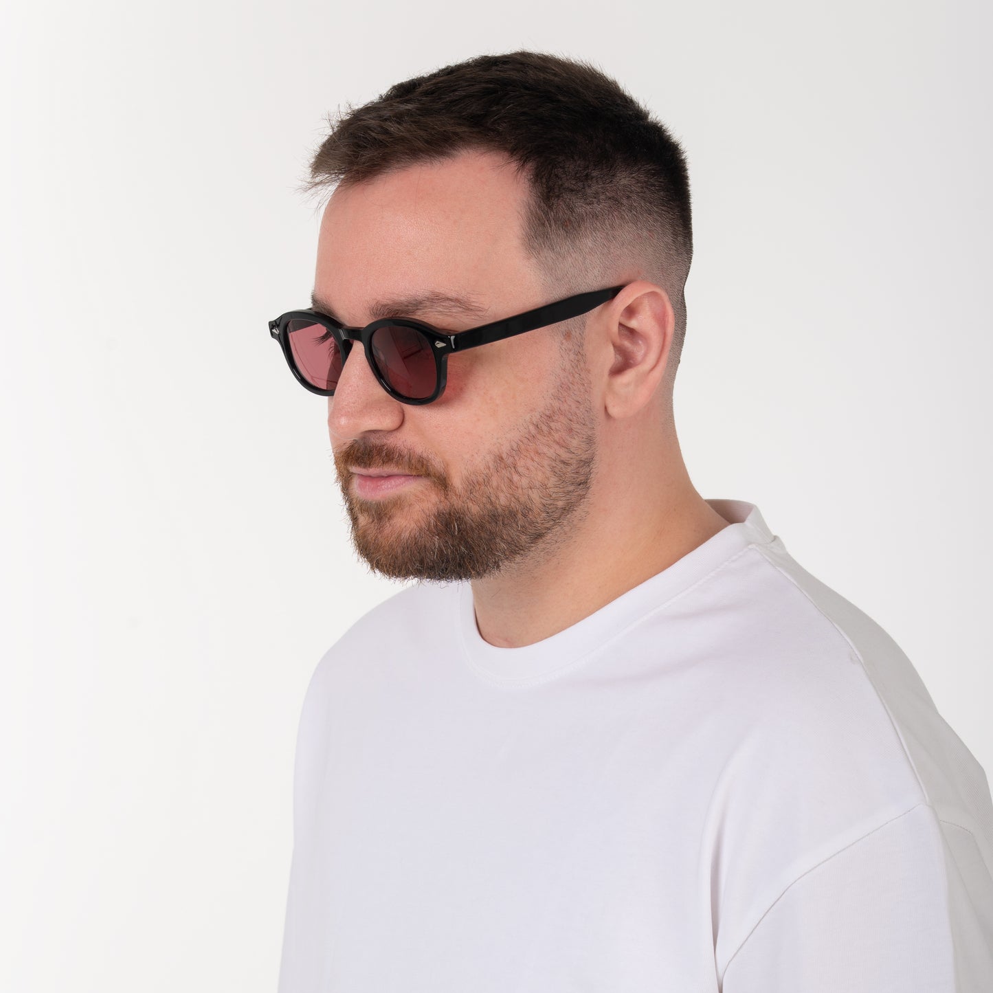 Man wearing black sunglasses and a white shirt on a light gray background