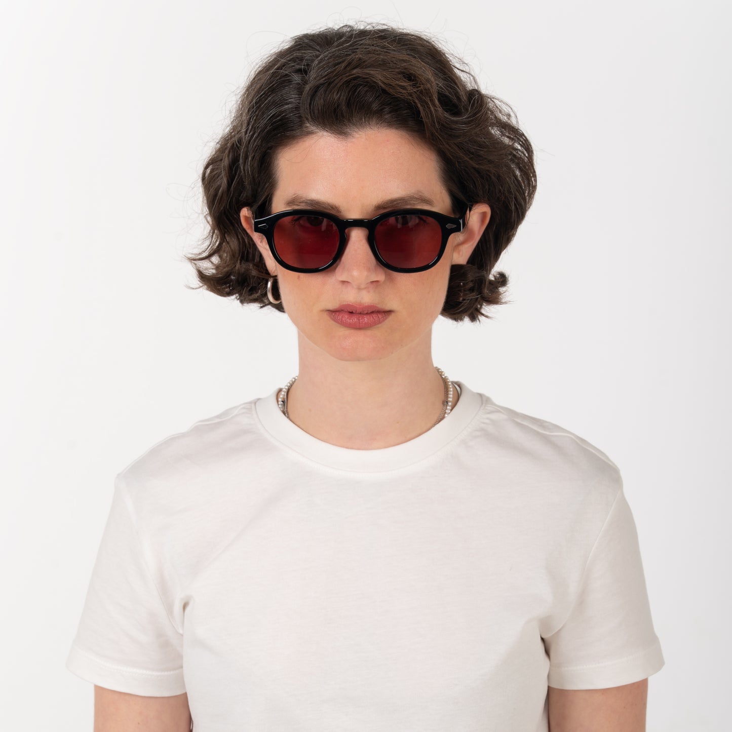 Person wearing red sunglasses and a white t-shirt on a plain background